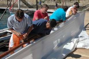 A tripulación prepara as velas para saír a navegar